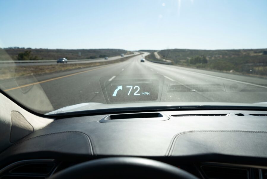 Daytime windshield head-up display showing 72 MPH and a navigation arrow on a highway