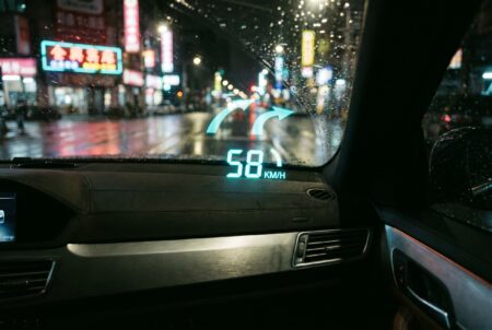 Car head-up display projecting speed and navigation on a windshield at night in the city