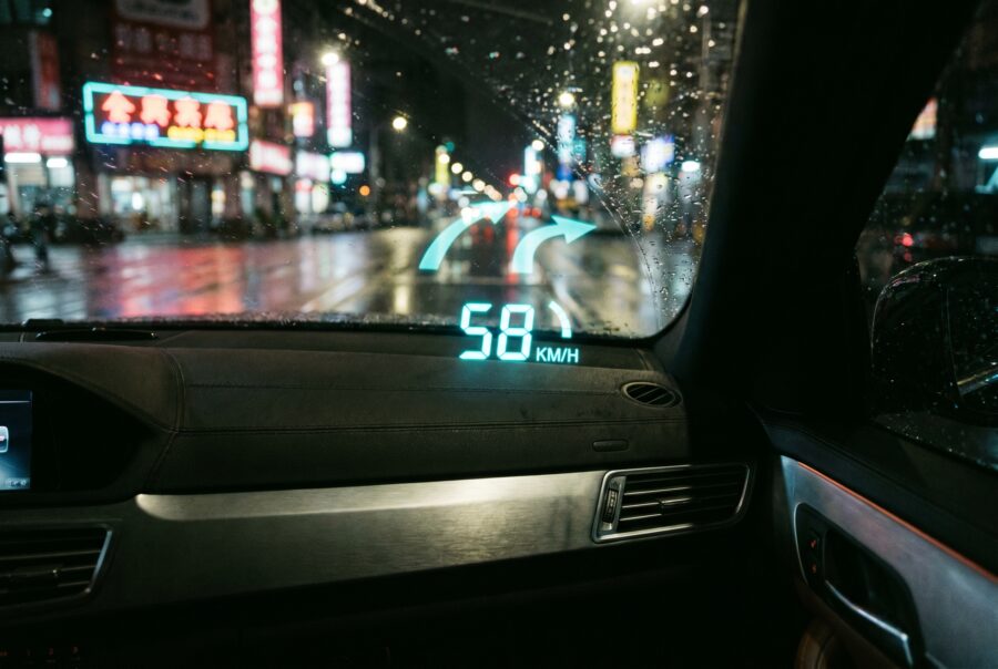Car head-up display projecting speed and navigation on a windshield at night in the city